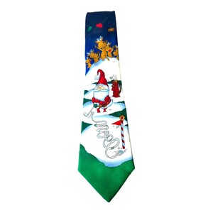 May include: A novelty Christmas tie featuring Santa Claus playing golf on a snowy course. The tie has a green, white, and blue color scheme with reindeer and golf-themed graphics. The tie is a festive accessory for the holiday season.