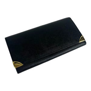 May include: Black wallet with gold-colored corner accents. The wallet has a textured surface and a rectangular shape. The wallet appears to be made of leather or a leather-like material. The wallet is closed and has a flap closure.