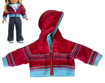 May include: A doll wearing a red and blue zip-up hooded jacket, a white t-shirt with a pink flower graphic, and dark blue jeans. A separate red and blue zip-up hooded jacket is shown in the foreground, featuring horizontal stripes and ribbed cuffs.