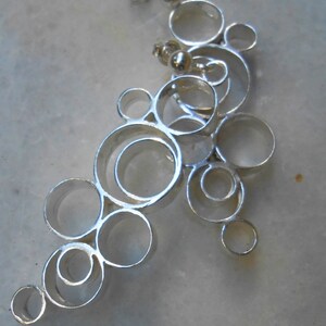 May include: Silver earrings with a design of interlocking circles, creating a cascading effect.