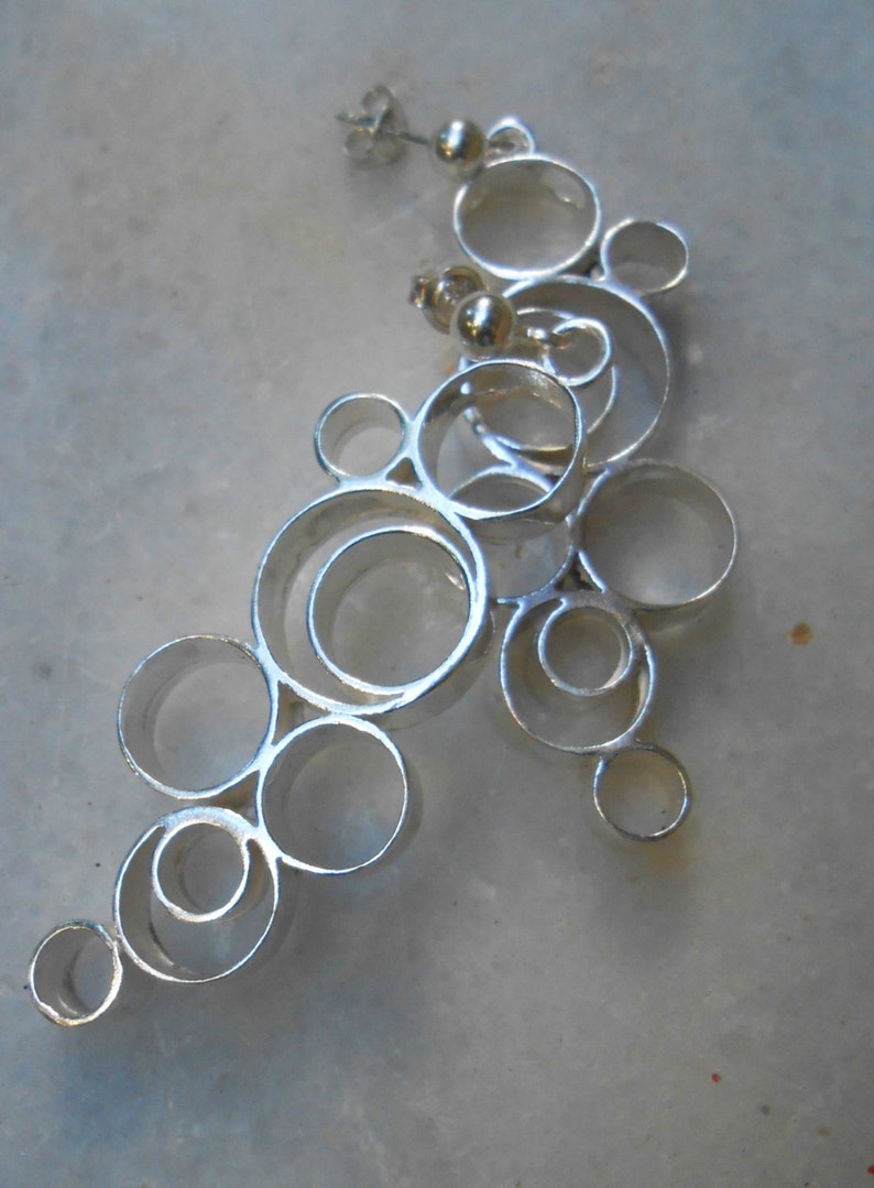 May include: Silver earrings with a design of interlocking circles, creating a cascading effect.