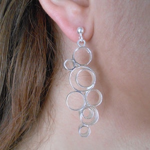 May include: Silver dangle earrings with a design of multiple interconnected circles.