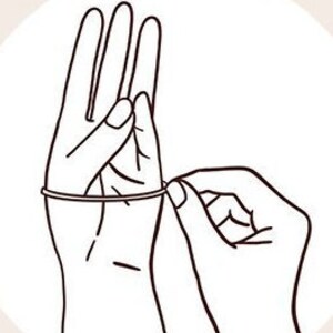 May include: A hand wearing a rubber glove is being pulled on by another hand. The glove is being pulled up the arm.