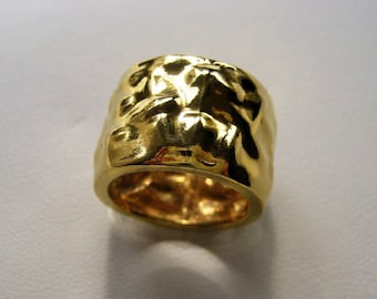 May include: A gold ring with a textured, hammered finish. The ring is wide and has a rounded shape.