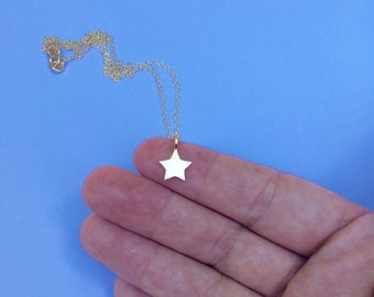 May include: A gold chain necklace with a small, flat, gold star pendant.