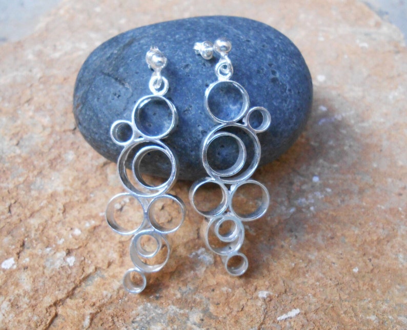 May include: A pair of silver dangle earrings with a design of multiple interconnected circles.
