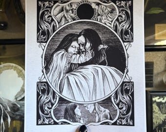 May include: Black and white art print featuring a romantic embrace within an ornate frame. The illustration depicts two figures in a tender moment, with intricate details and a gothic aesthetic. The print is held by a person.