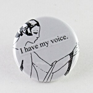 May include: A white button with a black and white illustration of a woman with the text "I have my voice."