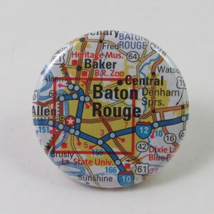 May include: A round button with a map of Baton Rouge, Louisiana. The map shows major roads and highways, including Interstate 12, and points of interest like the Baton Rouge Zoo and Louisiana State University.