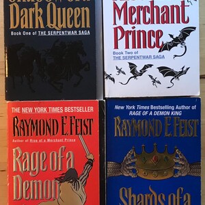 May include: Four fantasy novel book covers by Raymond E. Feist. The covers feature illustrations of dragons, a demon king, and a crown. The titles are "Shadow of a Dark Queen", "Rise of a Merchant Prince", "Rage of a Demon King", and "Shards of a Broken Crown".