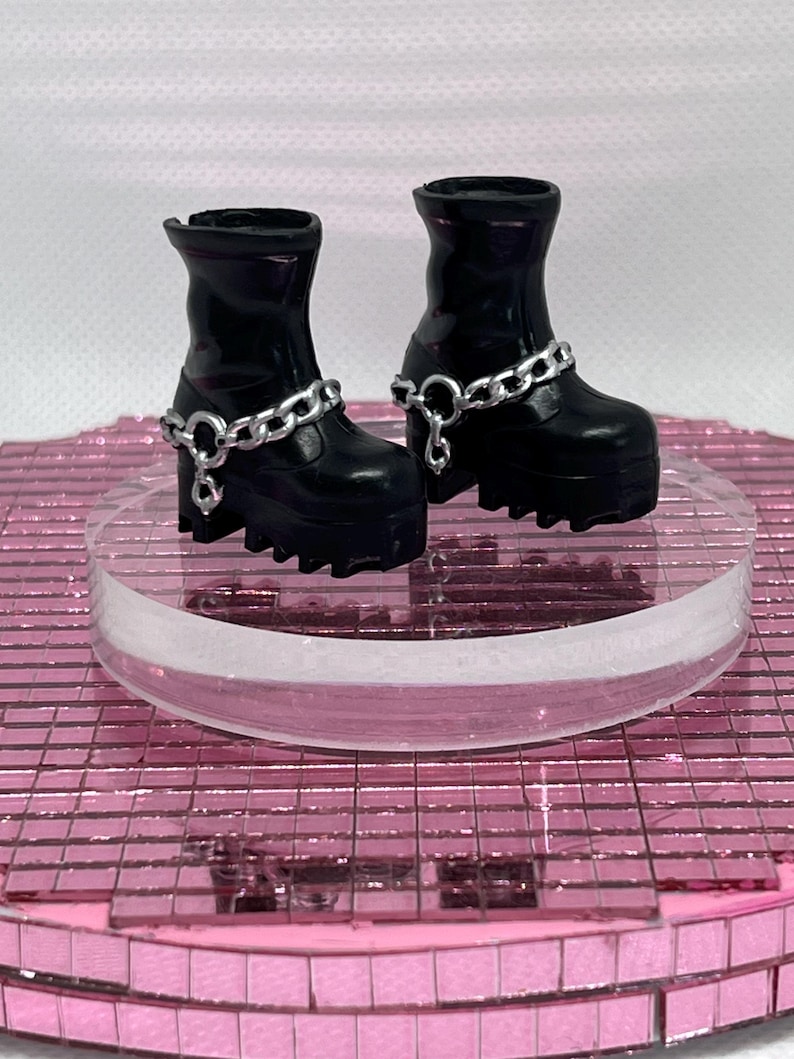 May include: A pair of black platform boots with silver chain accents. The boots have a chunky heel and a rounded toe.