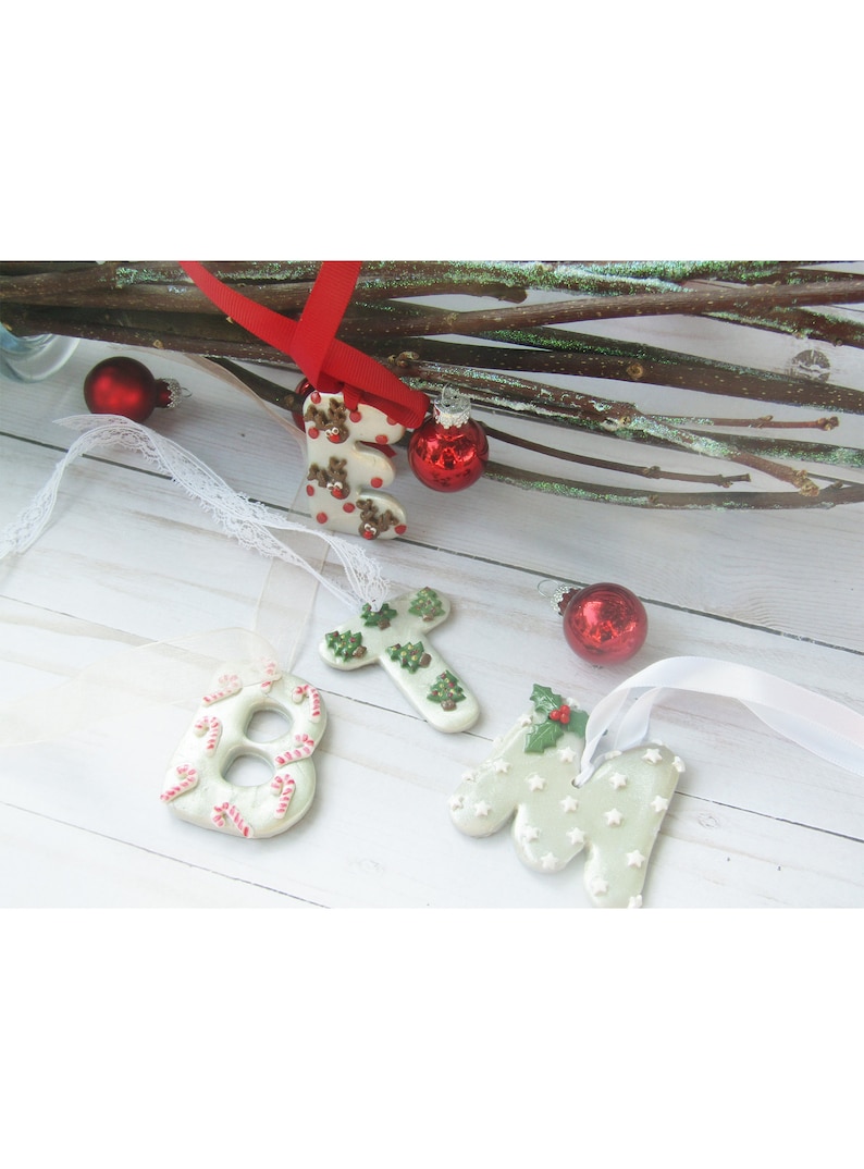 May include: Christmas-themed ornaments in the shape of letters and numbers, including the letters "E" and "N", and the number "8". The ornaments are white with red and green accents, and are decorated with reindeer, candy canes, and stars.