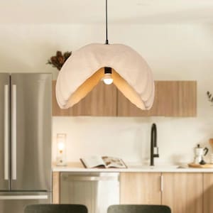 Puede incluir: Una cocina moderna con una mesa y sillas de madera clara. Una lámpara colgante de color crema cuelga sobre la mesa. La cocina cuenta con electrodomésticos de acero inoxidable y gabinetes de madera clara, creando un espacio luminoso.
