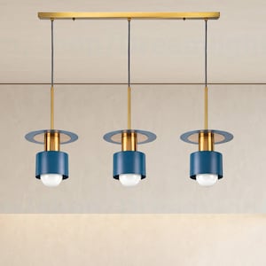 May include: Three blue and gold pendant lights hang from a ceiling track in a modern kitchen. The lights have a circular shade with a flat top and a cylindrical bottom.