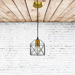Puede incluir: Una lámpara colgante geométrica negra con acabado dorado cuelga de un techo de madera. La lámpara tiene un diseño de jaula con una sola bombilla en su interior.