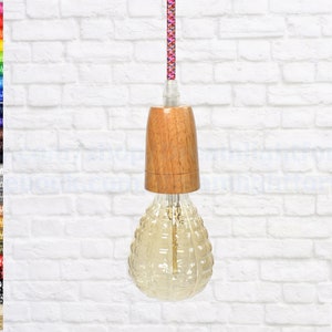 May include: A light bulb with a textured glass globe and a wooden ceiling fixture. The cord is a pink and white braided fabric.