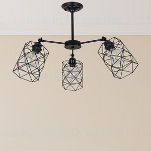 May include: A black ceiling light fixture with three geometric wire cage shades. Each shade has a clear light bulb inside.