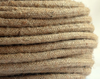 Puede incluir: Primer plano de una cuerda gruesa de fibra natural enrollada en forma circular. La cuerda es de color marrón claro y tiene una superficie rugosa y texturizada.