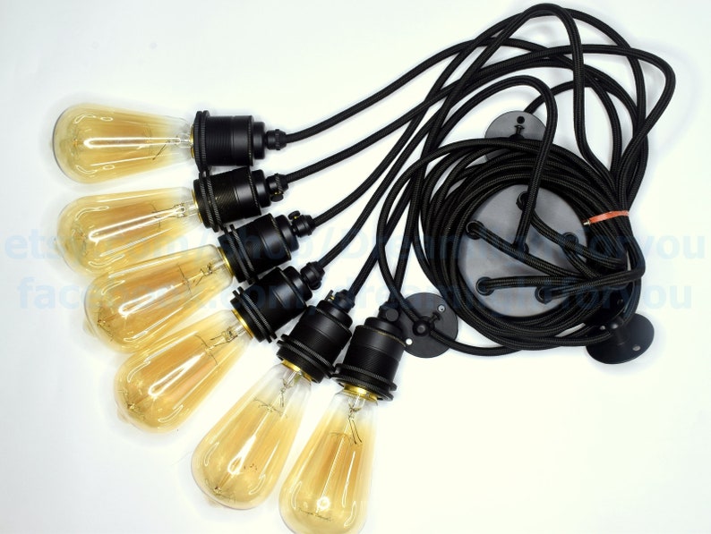 May include: A set of six black pendant light fixtures with clear glass bulbs. The fixtures are connected by black cords and have a black metal base.
