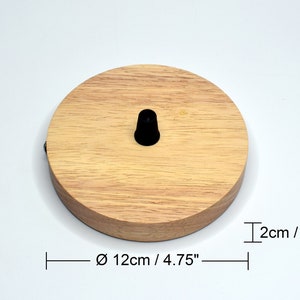 May include: A round wooden ceiling rose with a black cord grip. The ceiling rose measures 4.75 inches in diameter and 0.8 inches in height.
