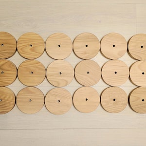 May include: A set of 18 wooden circles with a hole in the center. The circles are arranged in a rectangular pattern.