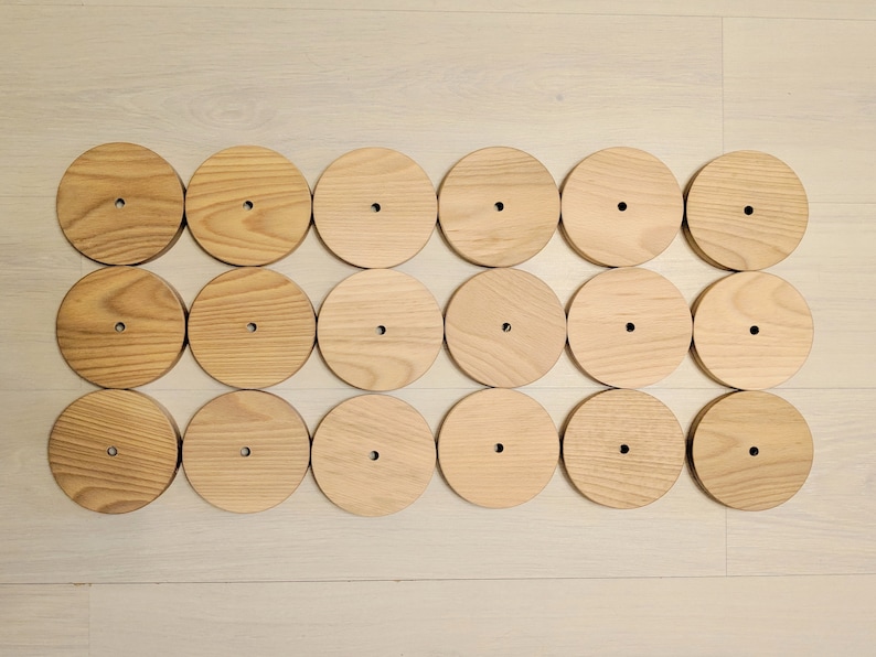 May include: A set of 18 wooden circles with a hole in the center. The circles are arranged in a rectangular pattern.