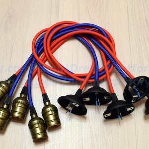 Peut inclure: Six douilles de lampe dorées avec des cordons tressés rouges et bleus et des bases en plastique noir. Les cordons sont torsadés.