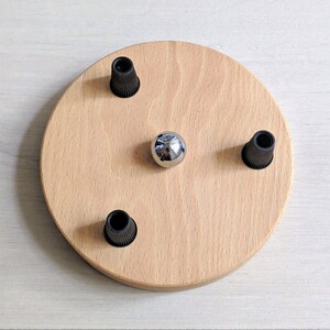May include: A round wooden ceiling plate with three black electrical cord holders and a silver metal ball in the center.