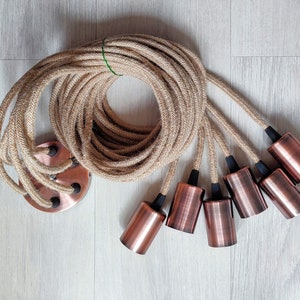 May include: A set of six copper-colored light bulb sockets with black accents, connected by a long length of natural jute rope.