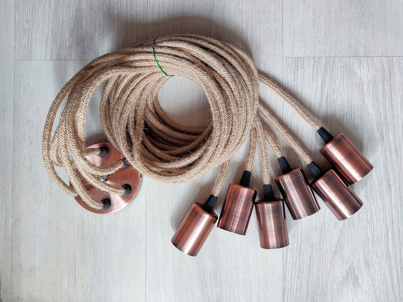 May include: A set of six copper-colored light bulb sockets with black accents, connected by a long length of natural jute rope.