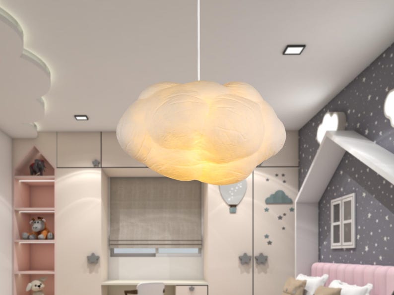 May include: A white cloud-shaped pendant light fixture suspended from the ceiling by a thin cord. The lamp features a textured, rounded surface that emits a soft, warm glow from within, creating a diffused light effect throughout the space.