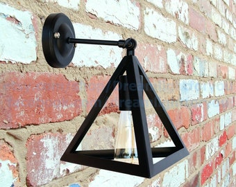 May include: Black metal wall sconce with a triangular shade and a single light bulb. The sconce is mounted on a brick wall.