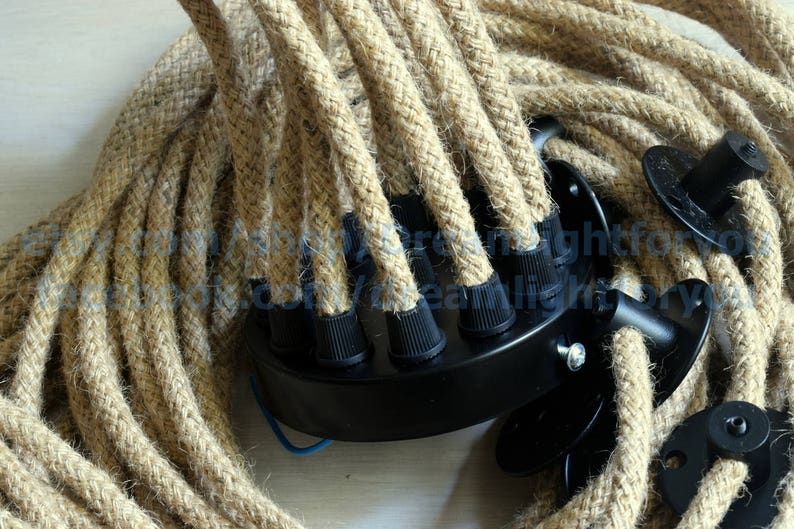 May include: Close-up of a multi-strand, natural rope cord with black electrical connectors. The rope is woven and has a natural, rustic look.