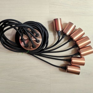 May include: A black electrical cord with six copper lamp sockets. The cord is coiled and the sockets are arranged in a fan shape.