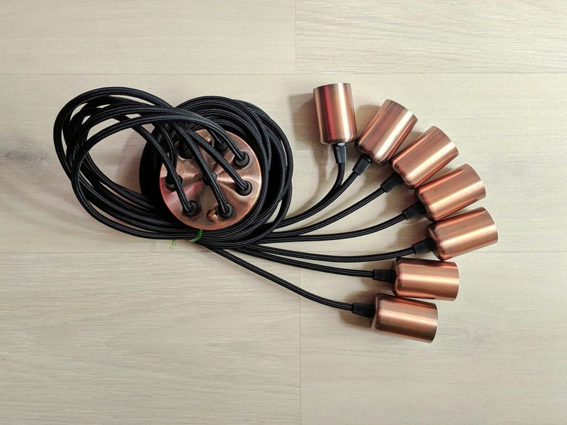 May include: A black electrical cord with six copper lamp sockets. The cord is coiled and the sockets are arranged in a fan shape.