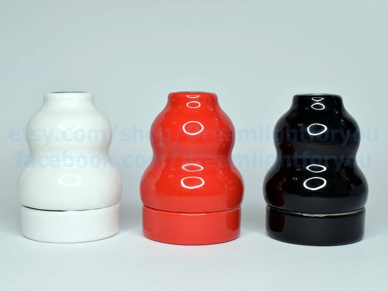 May include: Three ceramic vases in different colors: white, red, and black. Each vase has a rounded, bulbous shape with a slightly indented middle section. The vases are all the same size and shape.