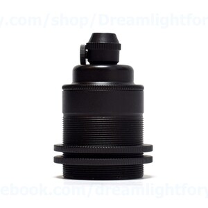 May include: Black metal lamp socket with a threaded base and a screw-on top. The socket is designed for use with standard light bulbs.