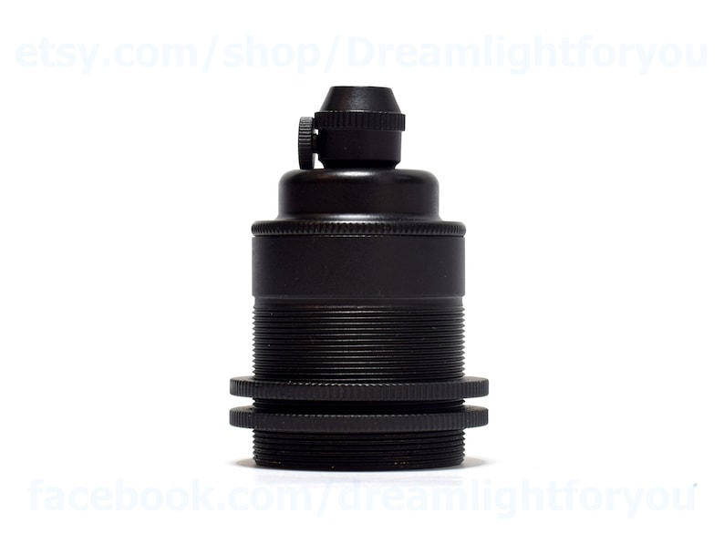 May include: Black metal lamp socket with a threaded base and a screw-on top. The socket is designed for use with standard light bulbs.