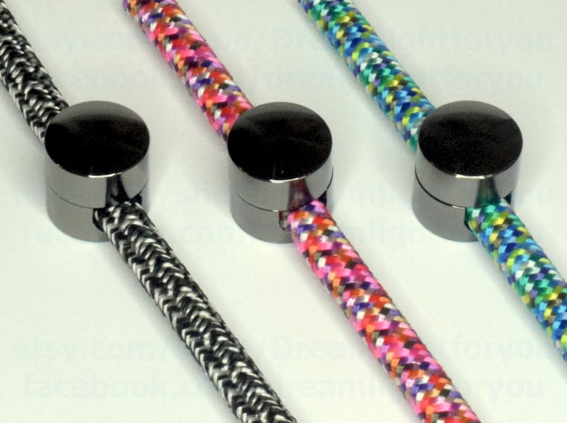 May include: Three black metal cord end caps with different colored braided cords. The cords are black and white, pink and white, and blue and green.