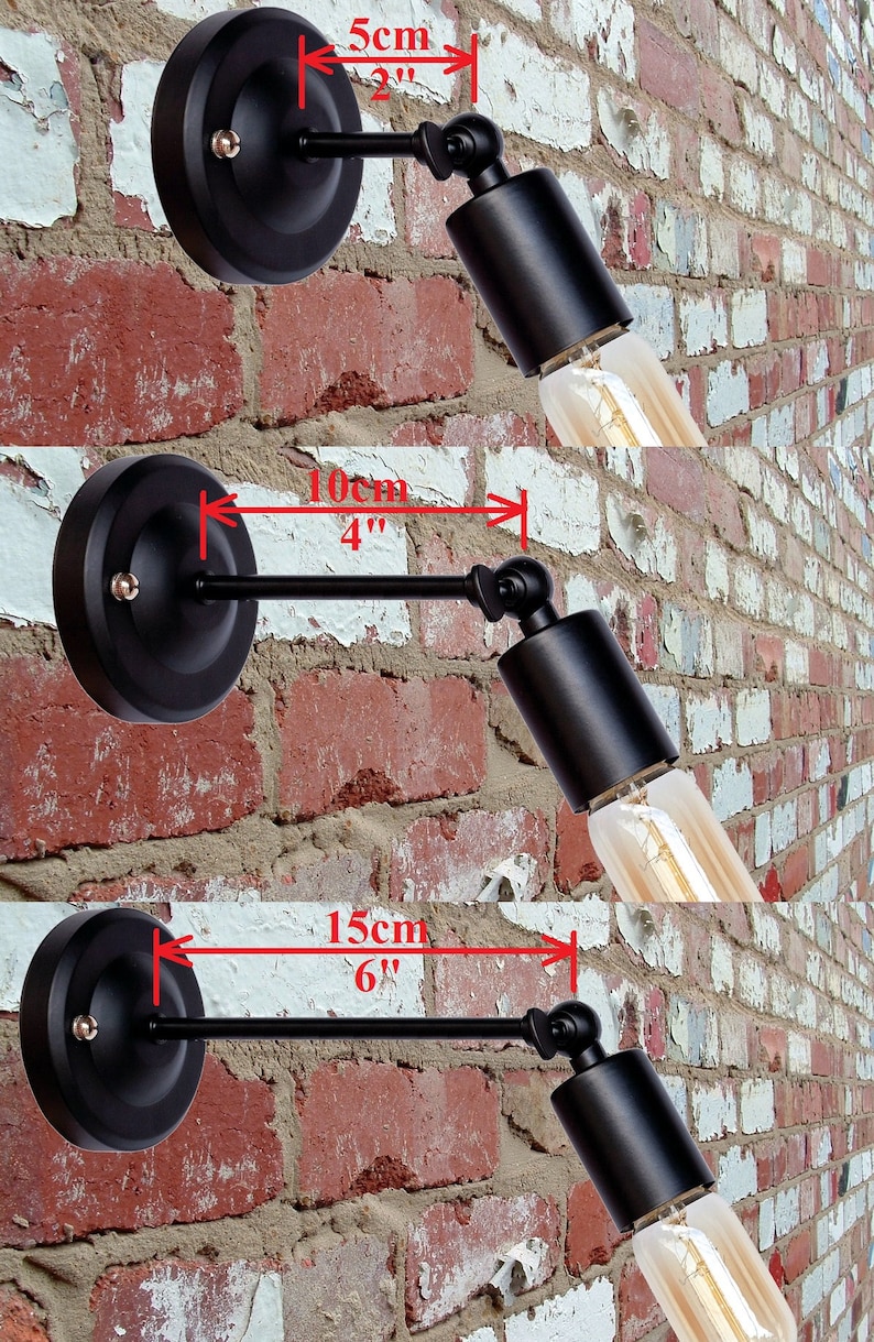 K&ouml;nnte beinhalten: Drei schwarze Wandleuchten mit verstellbaren Armen. Die Arme sind 5 cm, 10 cm und 15 cm lang. Die Leuchten sind vor einer Backsteinwand abgebildet.