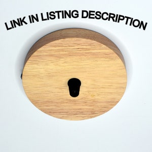 K&ouml;nnte beinhalten: Eine runde Holz-Deckenabdeckung mit einem schwarzen Loch in der Mitte. Die Abdeckung ist aus hellem Holz mit nat&uuml;rlicher Maserung. "LINK IN LISTING DESCRIPTION" ist in schwarzer Schrift auf wei&szlig;em Hintergrund &uuml;ber der Abdeckung gedruckt.