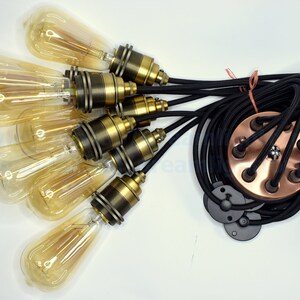 May include: A six-light pendant light kit with black braided cord and copper ceiling plate. The kit includes six clear glass bulbs with gold-tone metal sockets.