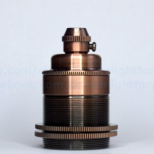 May include: A copper-colored light bulb socket with a threaded base and a small screw on the top.