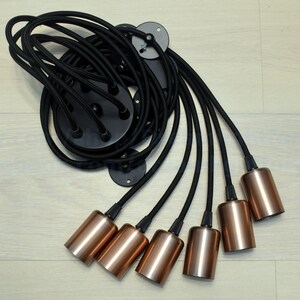 May include: A black ceiling light fixture with six copper-colored lampshades hanging from black cords.
