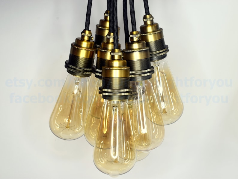 May include: A cluster of six antique brass pendant light fixtures with clear glass bulbs hanging from black cords.