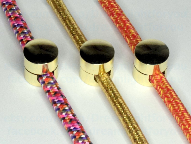 May include: Three gold cord end caps with different colored cords threaded through them. The cords are pink, yellow, and red.