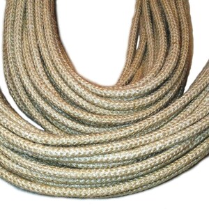 May include: A close-up of a thick, natural-fiber rope, likely jute or sisal, in a light beige color. The rope is coiled and twisted, showcasing its texture and strength.