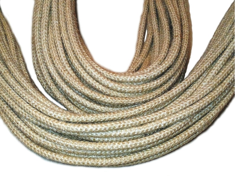 May include: A close-up of a thick, natural-fiber rope, likely jute or sisal, in a light beige color. The rope is coiled and twisted, showcasing its texture and strength.