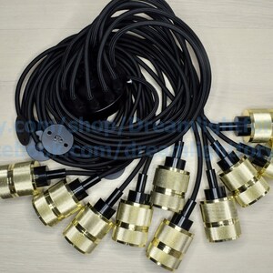Puede incluir: Un conjunto de 8 l&aacute;mparas colgantes de color dorado con cables negros. Los cables est&aacute;n agrupados y listos para colgarse.