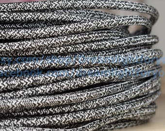 Puede incluir: Primer plano de un cable trenzado blanco y negro. El cable tiene un patrón en zigzag y está enrollado.